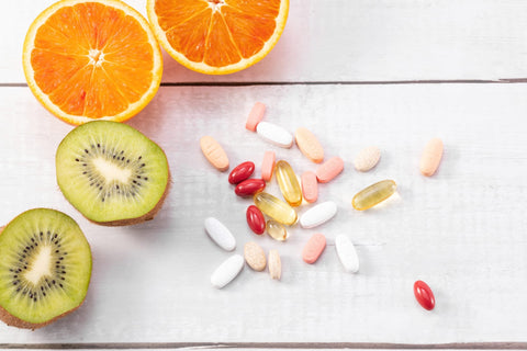 A selection of vitamins and fruit on a table.